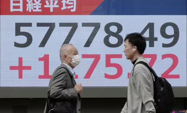 People walk in front of an electronic stock board showing Japan's Nikkei index at a securities firm Tuesday, April 14, 2026, in Tokyo. (AP Photo/Eugene Hoshiko)