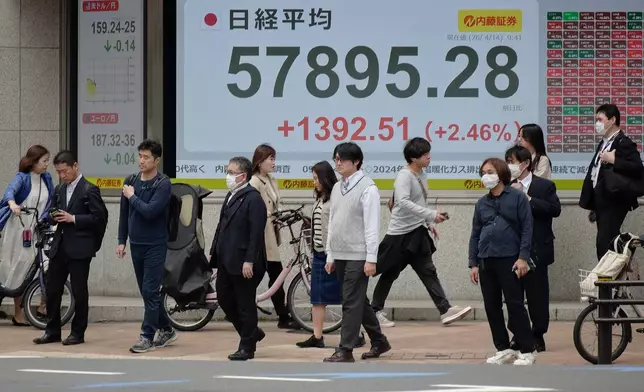 People walk in front of an electronic stock board showing Japan's Nikkei index at a securities firm Tuesday, April 14, 2026, in Tokyo. (AP Photo/Eugene Hoshiko)