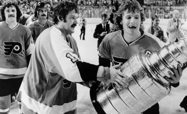 FILE - Philadelphia Flyers' Bernie Parent, left, and Bobby Clarke, carry the Stanley Cup off the ice in Buffalo, May 28, 1975 after defeating the Buffalo Sabres. (AP Photo/File)