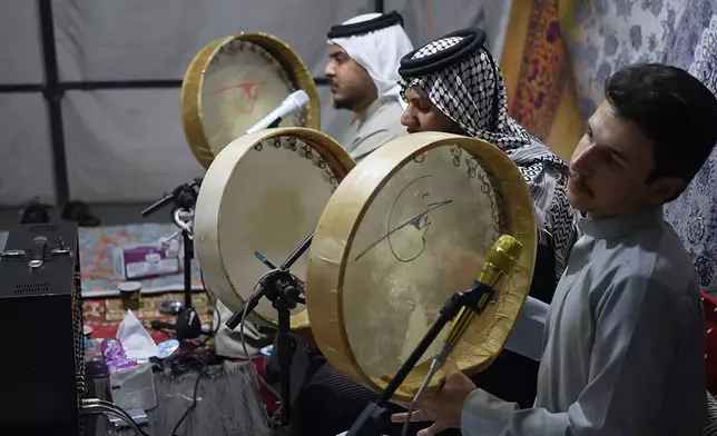 Musicians beat the daf drum as they perform traditional mourning songs for men gathered under a tent outside the family home of Iraqi singer Sajida Obaid on the seventh day of her passing in Irbil, Iraq, Thursday, April 10, 2026. (AP Photo/Stella Martany)
