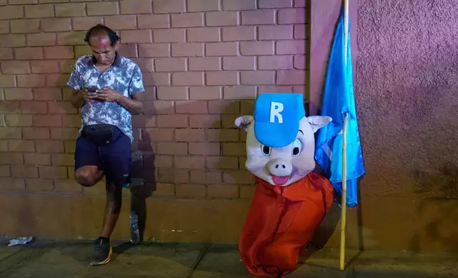 FILE - A supporter of Popular Renewal presidential candidate Rafael López Aliaga, who has embraced the name nickname “Porky”, leans a against a wall alongside his “Porky” costume, in Lima, Peru, March 31, 2026. (AP Photo/Martin Mejia, File)