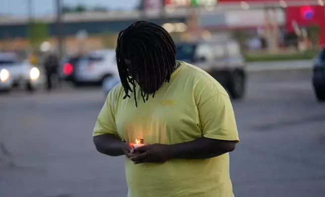 A man holds a candle during a prayer vigil for the victims of a mass shooting earlier in the day, Sunday, April 19, 2026, in Shreveport, La. (AP Photo/Gerald Herbert)