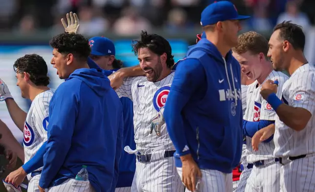 Chicago Cubs' Dansby Swanson, center, celebrates with teammates after driving in the game-winning run in the 10th inning of a baseball game against the Philadelphia Phillies, Thursday, April 23, 2026, in Chicago. (AP Photo/Erin Hooley)