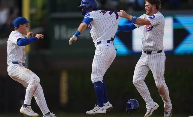 Chicago Cubs' Dansby Swanson, center, celebrates with Carson Kelly, right, and Matt Shaw after driving in the game-winning run in the 10th inning of a baseball game against the Philadelphia Phillies, Thursday, April 23, 2026, in Chicago. (AP Photo/Erin Hooley)