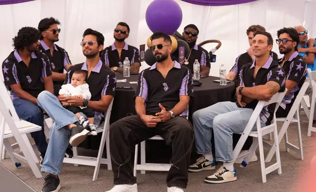 Unmurkt Chand holds his baby, Krishay, with members of the Los Angeles Knight Riders, cricket team form a LA sign with their hands as they pose for a picture at the Pomona Fairplex on Wednesday, April 22, 2026, during the groundbreaking ceremony of the new Knight Riders Cricket Field, which will serve as the Los Angeles Knight Riders' official home field for 2026 and later host cricket at the LA 2028 Olympics. (AP Photo/Damian Dovarganes)