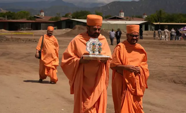 BAPS Shri Swaminarayan Mandir temple Hindu monks walk after performing a Puja ceremony, a traditional blessing ritual for the groundbreaking ceremony for the official home field for the Los Angeles Knight Riders for 2026, and the future venue of the LA 2028 Olympics Fairgrounds Cricket Stadium at the Pomona Fairplex in Pomona, Calif., Wednesday, April 22, 2026. (AP Photo/Damian Dovarganes)