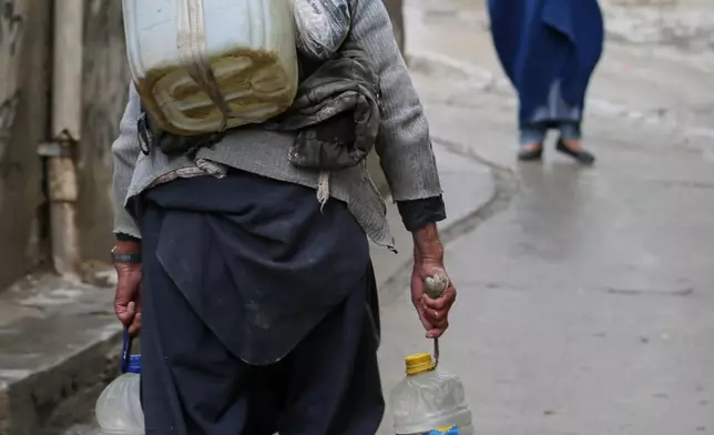 A man carries plastic bottles and a jerrycan on his back after collecting water from a well at a mosque in Deh Mazang, Kabul, Afghanistan, Thursday, April 2, 2026. (AP Photo/Siddiqullah Alizai)