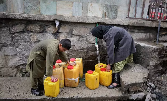 A boy and a girl collect water from a hose connected to a well at a mosque in Deh Mazang, Kabul, Afghanistan, Thursday, April 2, 2026. (AP Photo/Siddiqullah Alizai)