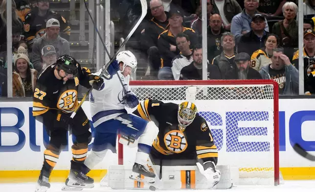 Tampa Bay Lightning center Brayden Point, center, battles for a loose puck with Boston Bruins defenseman Hampus Lindholm (27) in front of Bruins goaltender Jeremy Swayman during an NHL hockey game, Saturday, April 11, 2026, in Boston. (AP Photo/Robert F. Bukaty)