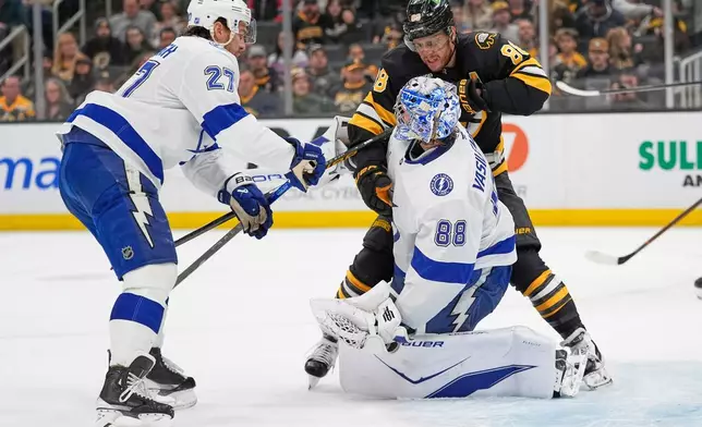 Boston Bruins right wing David Pastrnak (88) gets tangled with Tampa Bay Lightning goaltender Andrei Vasilevskiy (88) during the first period of an NHL hockey game, Saturday, April 11, 2026, in Boston. (AP Photo/Robert F. Bukaty)