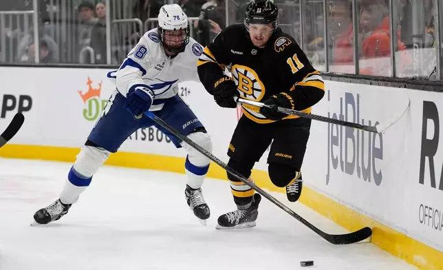 Boston Bruins center Casey Mittelstadt (11) and Tampa Bay Lightning defenseman Emil Lilleberg (78) chase the puck behind the Lightning net during the first period of an NHL hockey game, Saturday, April 11, 2026, in Boston. (AP Photo/Robert F. Bukaty)