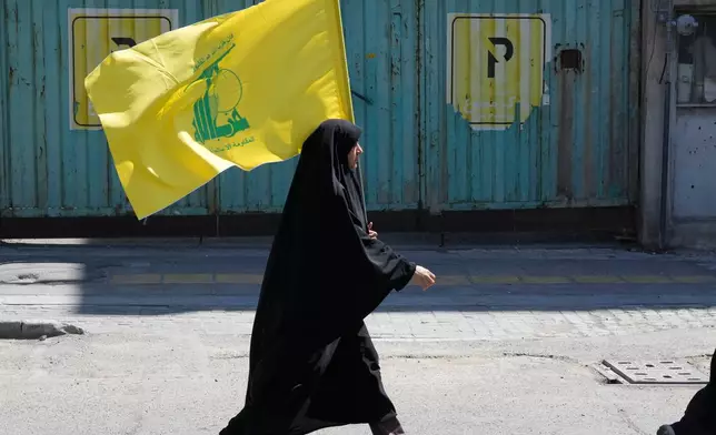 A woman carries a flag of Lebanon's militant Hezbollah group during a ceremony marking the 40th day since the death of Iranian Supreme Leader Ayatollah Ali Khamenei in Tehran, Iran, Thursday, April 9, 2026. (AP Photo/Vahid Salemi)