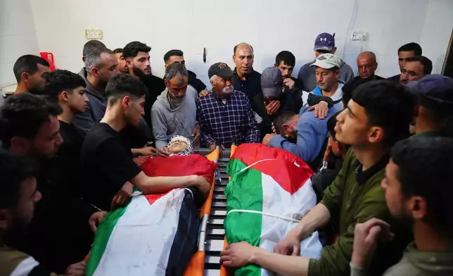 Mourners gather around the bodies of Aws al-Na'san and Jihad Abu Naim, residents of the West Bank village of al-Mughayyir, at the hospital's morgue in the West Bank city of Ramallah, Tuesday, April 21, 2026. (AP Photo/Mahmoud Illean)
