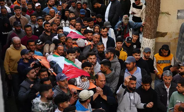 Mourners carry the bodies of Aws al-Na'san and Jihad Abu Naim, residents of the West Bank village of al-Mughayyir, out of the hospital's morgue in the West Bank city of Ramallah, Tuesday, April 21, 2026. (AP Photo/Mahmoud Illean)