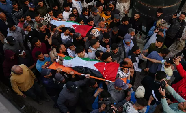 Mourners carry the bodies of Aws al-Na'san and Jihad Abu Naim, residents of the West Bank village of al-Mughayyir, out of the hospital's morgue in the West Bank city of Ramallah, Tuesday, April 21, 2026. (AP Photo/Mahmoud Illean)