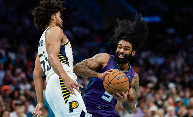Charlotte Hornets guard Coby White, right, drives into Indiana Pacers guard Ethan Thompson, left, during the first half of an NBA basketball game in Charlotte, N.C., Friday, April 3, 2026. (AP Photo/Nell Redmond)