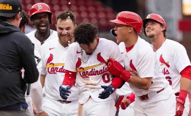 St. Louis Cardinal teammates surround Masyn Winn after he hit the game winning hit during the eleventh inning of a baseball game against the New York Mets Wednesday, April 1, 2026, in St. Louis. (AP Photo/LG Patterson)