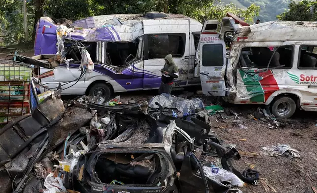 A man looks at vehicles damaged in an attack on the Pan-American Highway that killed at least a dozen people and authorities blamed on dissident groups of the former FARC rebels in Cajibio, Colombia, Sunday, April 26, 2026. (AP Photo/Santiago Saldarriaga)