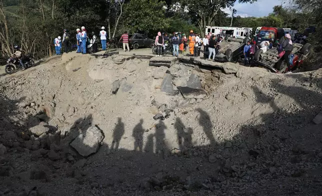 People look at vehicles damaged in an attack on the Pan-American Highway in Cajibio, Colombia, Saturday, April 25, 2026, that authorities said killed at least a dozen people and blamed on dissident groups of the former FARC rebels. (AP Photo/Santiago Saldarriaga)