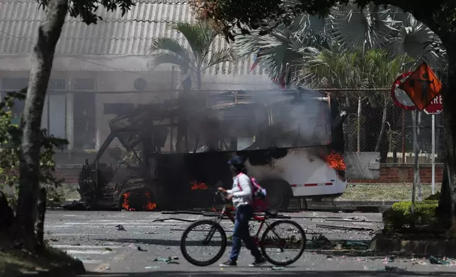 A bus burns after an explosion outside an army base in Cali, Colombia, Friday, April 24, 2026. (AP Photo/Santiago Saldariaga)