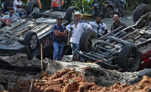 People stand at the site of an attack on the Pan-American Highway in Cajibio, Colombia, Sunday, April 26, 2026, where at least a dozen people were killed in an attack authorities blamed on dissident groups of the former FARC rebels. (AP Photo/Santiago Saldarriaga)