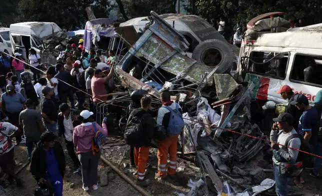 People gather around vehicles damaged in an attack on the Pan-American Highway in Cajibio, Colombia, Saturday, April 25, 2026, that killed at least a dozen people and authorities blamed on dissident groups of the former FARC rebels. (AP Photo/Santiago Saldarriaga)