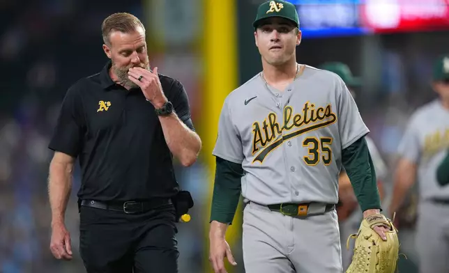 Athletics starting pitcher J.T. Ginn (35) leaves the field with head trainer Jeff Collins during the fourth inning of a baseball game against the Texas Rangers Sunday, April 26, 2026, in Arlington, Texas. (AP Photo/Julio Cortez)