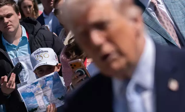 A boy holds up a rendering of an arch President Donald Trump proposed building to commemorate the United States' 250th anniversary as Trump speaks with reporters at the White House Easter Egg Roll on the South Lawn of the White House, Monday, April 6, 2026, in Washington. (AP Photo/Julia Demaree Nikhinson)