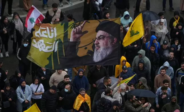 A Hezbollah supporter waves a flag with the portrait of the late Hezbollah leader Sayyed Hassan Nasrallah during a protest against the Lebanese Prime Minister Nawaf Salam, in front the government palace in Beirut, Lebanon, Friday, April 10, 2026. (AP Photo/Hussein Malla)