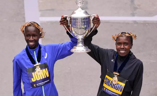 Boston Marathon winner John Korir of Kenya, left, hoists the trophy with women's division winner Sharon Lokedi also of Kenya, at the finish line of the Boston Marathon, Monday, April 20, 2026, in Boston. (AP Photo/Charles Krupa)