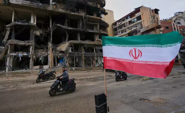 A man on his scooter passes next to an Iranian flag placed in front of a destroyed building, following a ceasefire between Hezbollah and Israel, in Dahiyeh, Beirut's southern suburbs, Lebanon, Monday, April 20, 2026. (AP Photo/Hussein Malla)