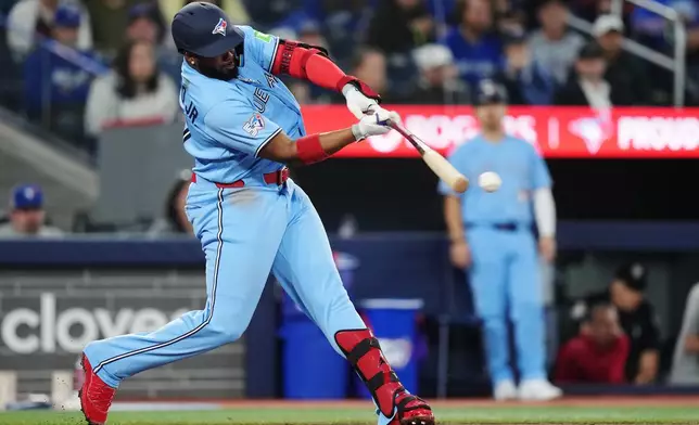 Toronto Blue Jays' Vladimir Guerrero Jr. (27) hits a single against the Colorado Rockies during the fourth inning of a baseball game in Toronto on Tuesday, March 31, 2026. (Nathan Denette/The Canadian Press via AP)