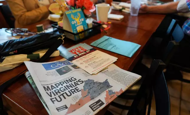 A print edition of the Goochland Gazette, with a front page story on the Virginia redistricting referendum, lies on a table at GG's Pizza as members of the Goochland Democratic Committee Jen Strozier, Doug Mock, Chris Svoboda, Richard Grebe and Judi Sheppard hold a lunch meeting on future get-out-the-vote efforts, Thursday, April 2, 2026, in Maiden, Va. (AP Photo/Julia Demaree Nikhinson)