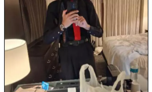 This image contained in a court filing by the Department of Justice, April 29, 2026, shows Cole Tomas Allen, left, inside his hotel room, on Saturday, April 25, 2026 in Washington, using his cellphone to take a photograph of himself in the mirror. (Department of Justice via AP)