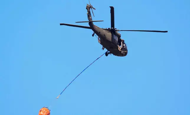 A helicopter carries water to the Brantley Highway 82 fire, Thursday, April 23, 2026, near Nahunta, Ga. (AP Photo/Mike Stewart)