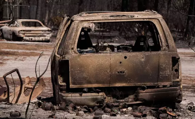 A burned vehicle sits near a destroyed home as the Brantley Highway 82 fire burns, Thursday, April 23, 2026, near Nahunta, Ga. (AP Photo/Mike Stewart)