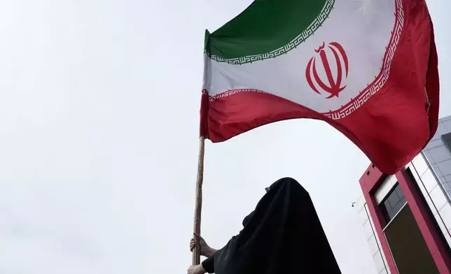 A woman holds an Iranian flag for a pro-government campaign in downtown Tehran, Iran, Saturday, April 25, 2026. (AP Photo/Vahid Salemi)