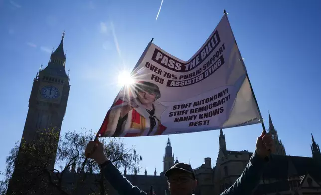 A campaigner holds a banner outside parliament in London as a proposed law to legalise assisted dying in England and Wales will run out of time on Friday, more than a year after MPs first voted in favour of it, Friday, April 24, 2026. (AP Photo/Kirsty Wigglesworth)