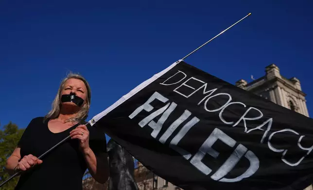 Campaigner Louise Shackleton holds a banner outside parliament in London as a proposed law to legalise assisted dying in England and Wales will run out of time on Friday, more than a year after MPs first voted in favour of it, Friday, April 24, 2026. (AP Photo/Kirsty Wigglesworth)