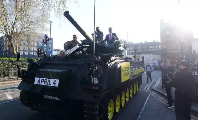 Derek Chisora, top left, arrives with Britain's Reform party leader Nigel Farage on top of a tank for a press conference in London, Thursday, April 2, 2026. (Adam Davy/PA via AP)