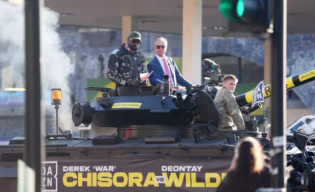 Derek Chisora, left, arrives with Britain's Reform party leader Nigel Farage on top of a tank for a press conference in London, Thursday, April 2, 2026. (Adam Davy/PA via AP)