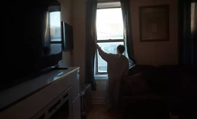 Gulhayo Yuldosheva's son, Heriberto, 11, looks through the window in an apartment building where tenants report maintenance issues and pest infestations, in the Bronx borough of New York, Tuesday, March 17, 2026. (AP Photo/Andres Kudacki)