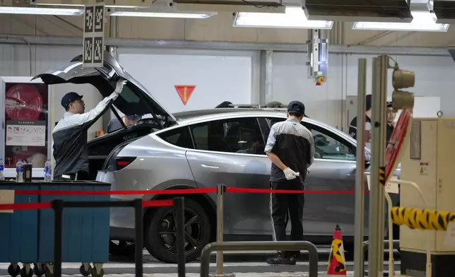 Workers check on the Tesla Model Y at the production lines at the Tesla Gigafactory assembly plant during a media organized tour, in Shanghai, China, Tuesday, April 14, 2026. (AP Photo/Andy Wong)