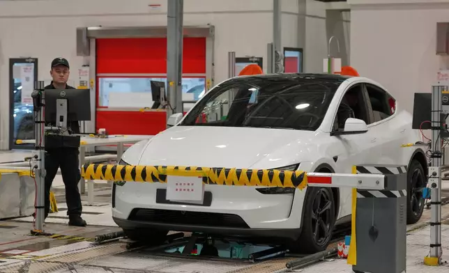 Workers inspect a Tesla Model Y at the production lines at the Tesla Gigafactory assembly plant during a media organized tour, in Shanghai, China, Tuesday, April 14, 2026. (AP Photo/Andy Wong)