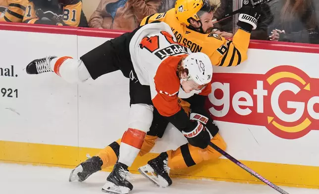 Philadelphia Flyers' Owen Tippett (74) checks Pittsburgh Penguins' Erik Karlsson, right, into the boards during the first period of Game 2 in the first round of the NHL Stanley Cup playoffs in Pittsburgh, Monday, April 20, 2026. (AP Photo/Gene J. Puskar)