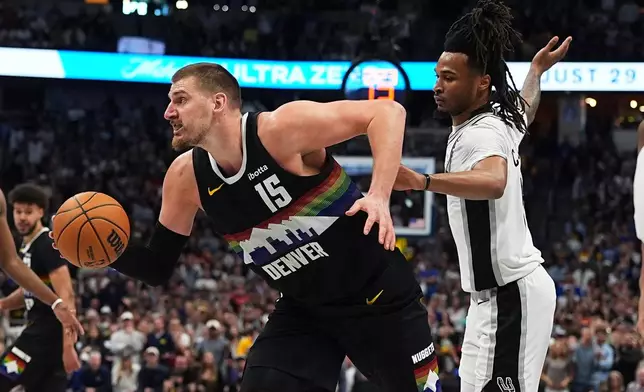 Denver Nuggets center Nikola Jokic, left, drives the lane past San Antonio Spurs guard Stephon Castle during overtime of an NBA basketball game Saturday, April 4, 2026, in Denver. (AP Photo/David Zalubowski)