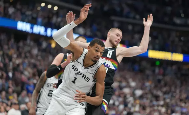 San Antonio Spurs center Victor Wembanyama, front, pursues a loose ball with Denver Nuggets guard Christian Braun in the second half of an NBA basketball game Saturday, April 4, 2026, in Denver. (AP Photo/David Zalubowski)