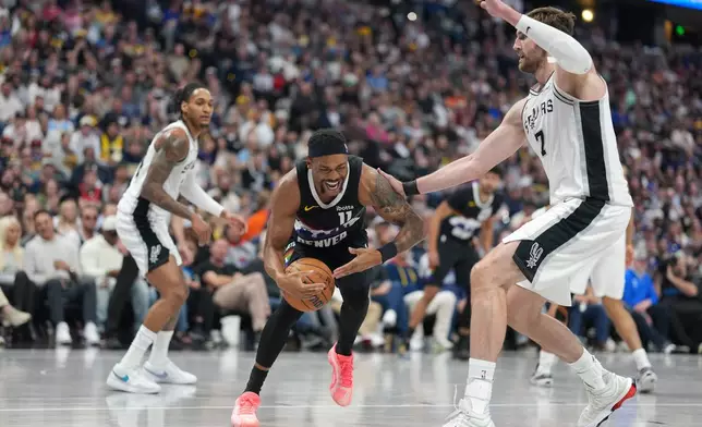 Denver Nuggets guard Bruce Brown, left, reacts after being injured while driving past San Antonio Spurs forward Luke Kornet in the second half of an NBA basketball game Saturday, April 4, 2026, in Denver. (AP Photo/David Zalubowski)