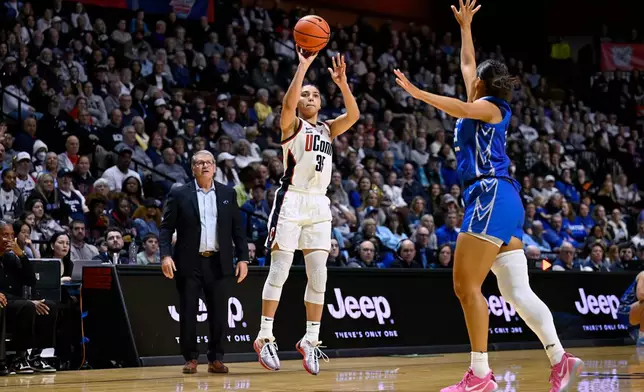 FILE - UConn guard Azzi Fudd (35) shoots over Creighton guard Jayme Horan (12) as UConn head coach Geno Auriemma looks on during the second half of an NCAA college basketball game in the finals of the Big East Conference tournament, Monday, March 10, 2025, in Uncasville, Conn. (AP Photo/Jessica Hill, File)