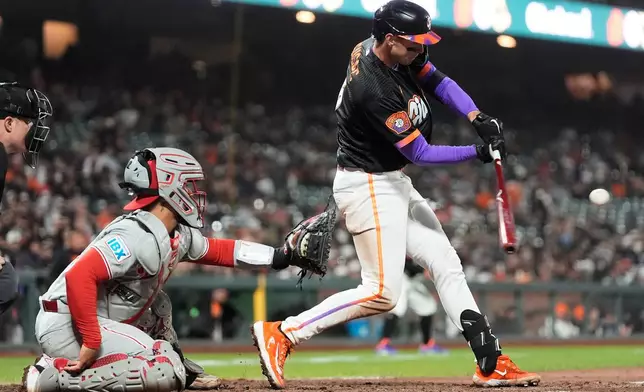 San Francisco Giants' Daniel Susac, right, hits a two-run triple next to Philadelphia Phillies catcher Rafael Marchán, left, during the eighth inning of a baseball game in San Francisco, Tuesday, April 7, 2026. (AP Photo/Jeff Chiu)